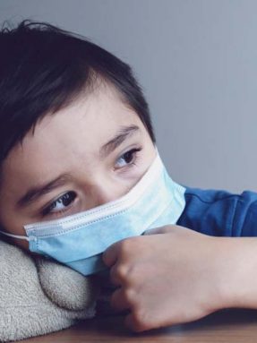 Child wearing medical face mask lying his head on teddy bear with crying tear,Emotional portrait of little boy crying and looking out deep in thought, Protective measures against spreading of Covid-19