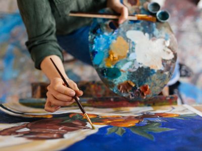 Top view of attractive woman hands drawing amazing picture on canvas in modern cozy art workshop