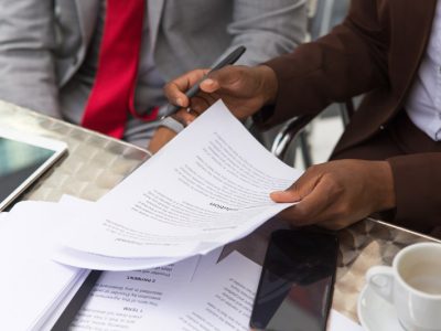 Businessman consulting legal expert in coffee shop. Closeup of business man and woman sitting in cafe and reading documents. Paperwork concept