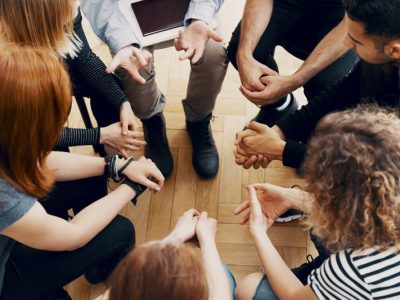 Close-up of hands of teenagers sitting in a circle during a support meeting