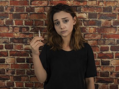 Portrait of young depressed girl holding cigarette. High quality photo